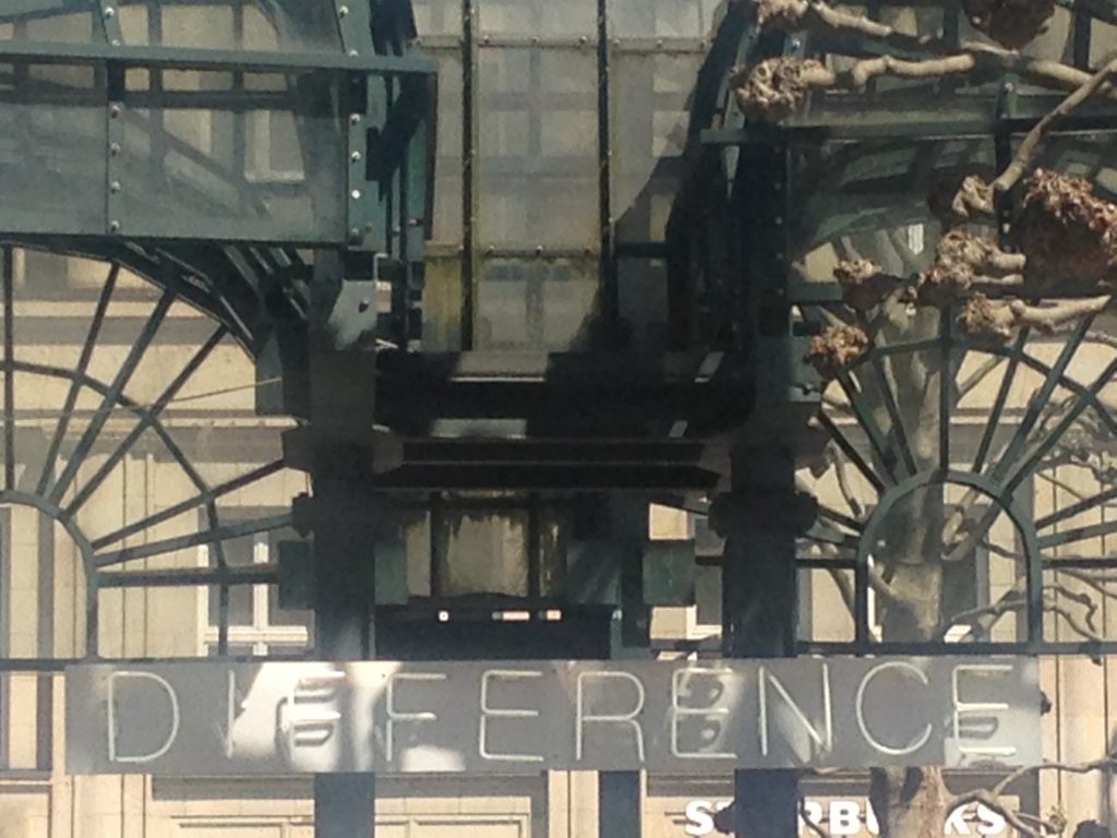 Das Foto zeigt die Fassade eines der Glaspavillions auf dem Rathausmarkt mit einem Schild mit der Aufschrift "DIFFERENECE".