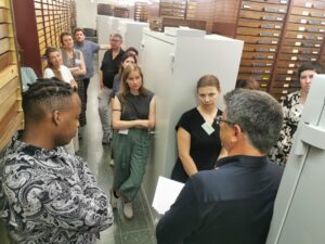 Eine Gruppe des Workshops steht in einer Sammlung des Zoologischen Museums und diskutiert mit Matthias Glaubrecht über Provenienzforschung zu naturkundlichen Sammlungen.