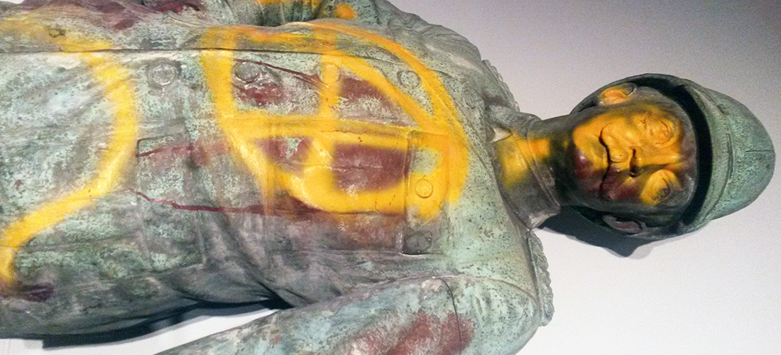 Das Foto zeigt die liegende Wissmann-Statue, die mit gelber Farbe angesprayed wurde. Die Statue präsentiert Wissman in militärischer Uniform.